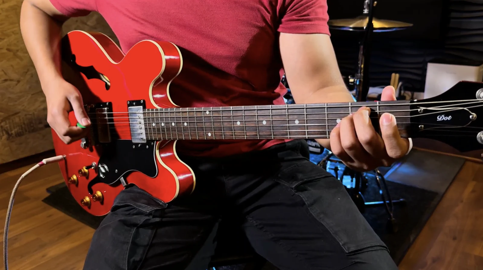 Persona tocando una guitarra eléctrica roja durante una clase.